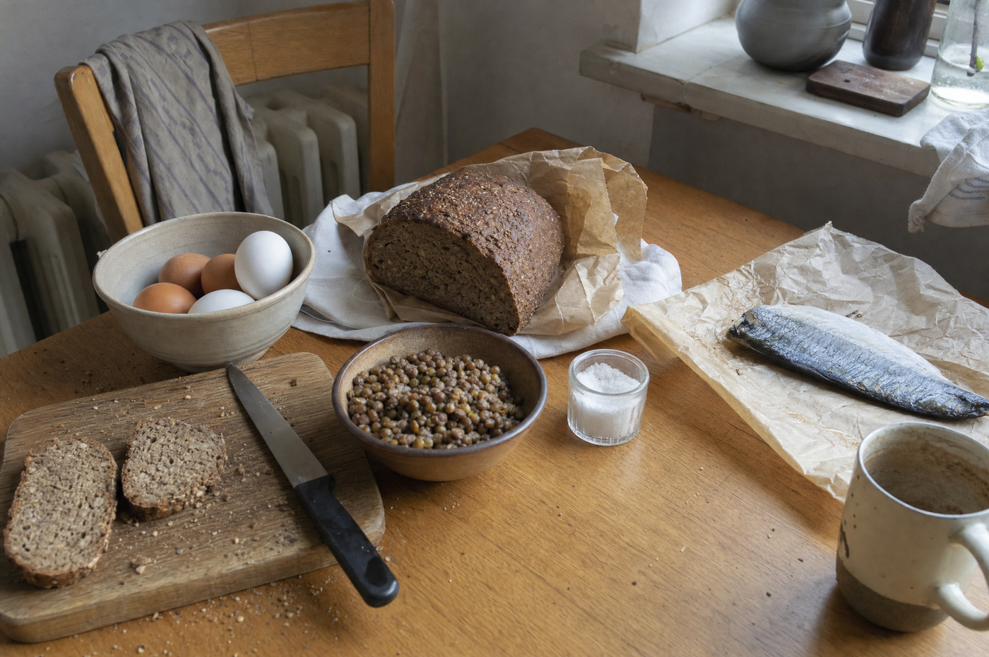 Küchentisch mit Eiern, Vollkornbrot, Linsen und Seefisch